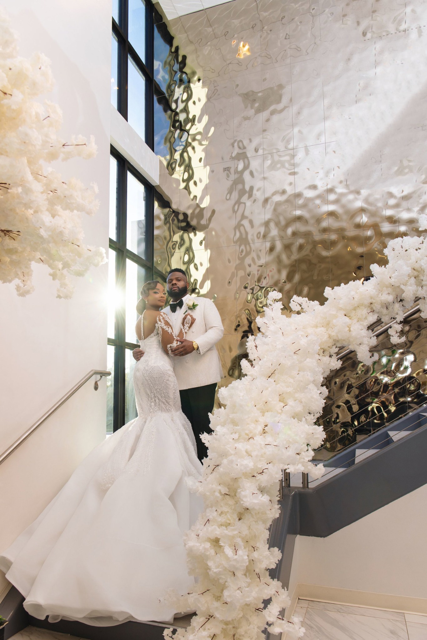 Wedding couple on a grand staircase surrounded by white flowers